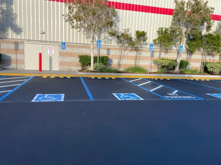 Blue ADA accessible stalls with ISA symbols on fresh sealcoat