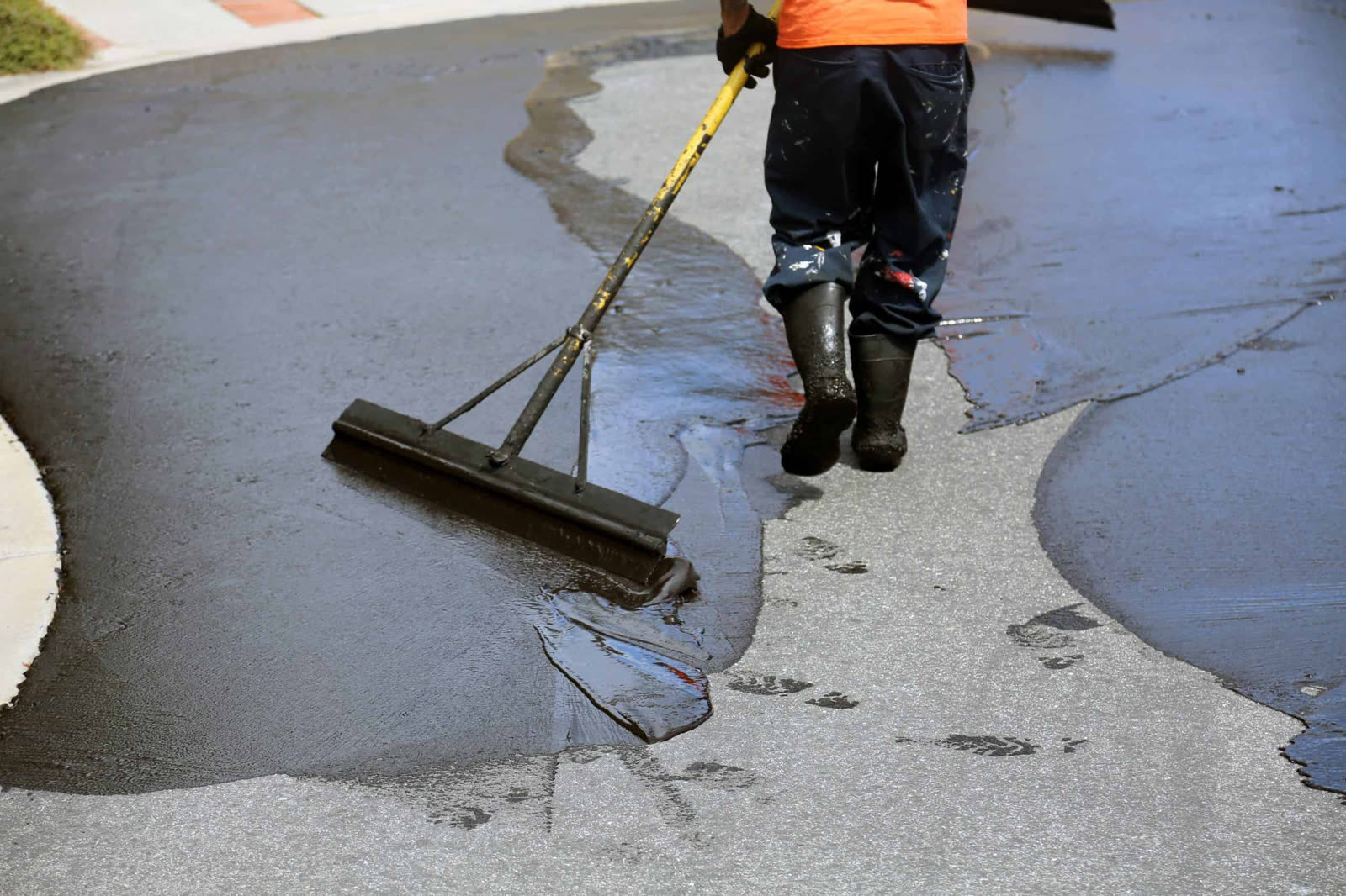 Crew member applying sealcoat with a squeegee